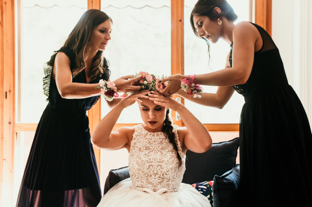 Le amiche della sposa la aiutano ad indossare la corona di fiori